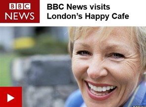 BBC news screenshot showing headline 'BBC news visits London Happy Cafe' with photo of woman smiling